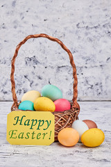 Easter greeting card, dyed eggs. Basket on wooden surface.