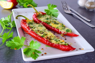 Oven cooked red paprika stuffed with cheese, garlic and herbs on a white plate with parcley and cherry tomatoes an abstract grey background. healthy eating concept. Mediterranean. Selective focus.