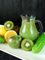 Green smoothie made of spinach, kiwi, cucumber, lemon and mint in different glass vessels for healthy nutrition