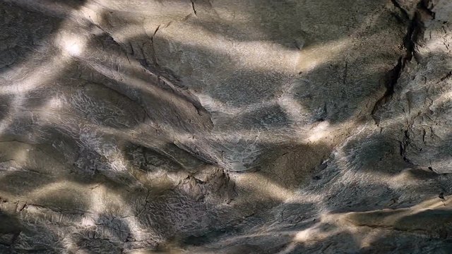 Water ripple caustic light reflections on stone wall