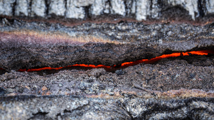 Hiking over the lava fields of Puu Oo, Big Island, Hawaii: View into a crack in the ground with molten magma glowing in the deep.