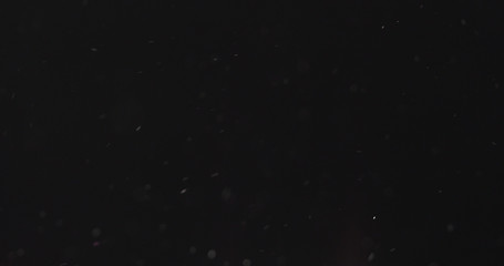 dust particles fast moving over black background from right, 4k photo