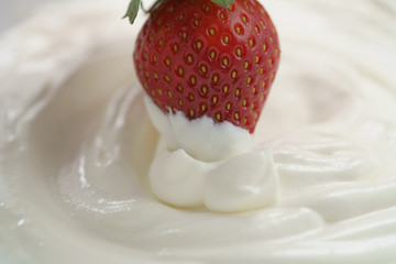 dipping fresh strawberry into cream, delicious food