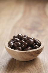 chocolate covered almonds in wood bowl on table, with copy space