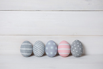 Four gray and one pink Easter egg on a wooden background. With retro filter effect
