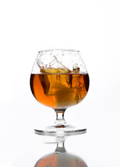 A glass of whiskey in which poured on a white background.
