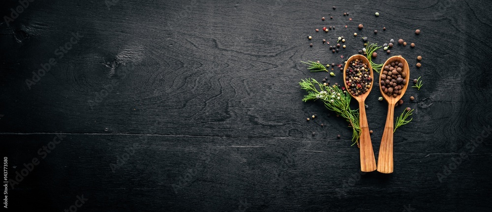 Wall mural A set of fragrant spices. A mixture of black and red pepper, coriander, paprika. On Wooden background. Top view. Free space.