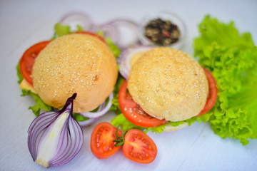Hamburger with cheese, meat, tomatoes and onions and herbs. On Wooden background. Top view. Free space.