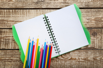 Drawing colourful pencils with notebook on brown wooden table