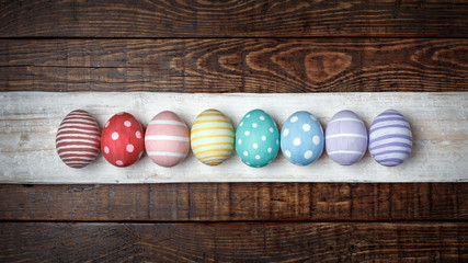Eight colorful handmade Easter eggs lie in a row on an old wooden background. Flat lay style