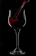 a glass of red wine which is poured on a black background