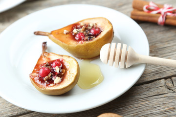 Baked pears with honey, walnuts and cranberries on grey wooden table