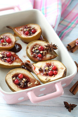 Baked pears with honey, walnuts and cranberries on white wooden table