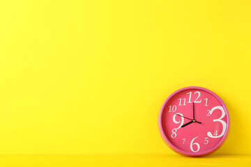 Pink round clock on yellow background