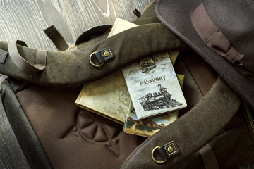 Hat, passport, backpack, notepad lie together for travel on wood floor