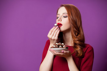 photo of beautiful young woman with plate full of chocolate candies on the wonderful purple...