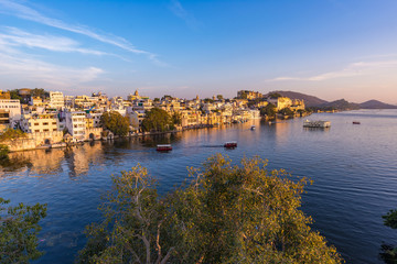 Obraz premium The famous city palace on Lake Pichola reflecting sunset light. Udaipur, travel destination and tourist attraction in Rajasthan, India