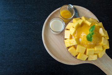 Bingsu mango (Korean food) on wooden plate on black table