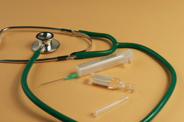 Stethoscope and syringe on orange background.
