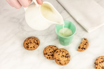 Milk poured into glass, with chocolate chips cookies