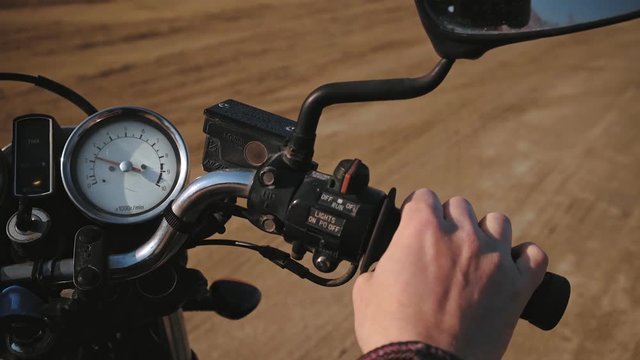 Side top view on male rider hand twists throttle grip on his classic bike to warm engine and tachometer level is shifting up and down.