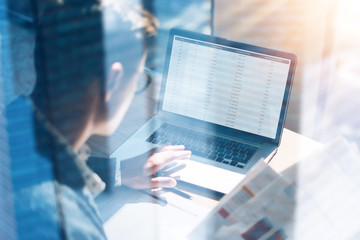 Closeup view of banking finance analyst in eyeglasses working at sunny office on laptop while sitting at wooden table.Businessman analyze stock report on notebook screen.Double exposure concept.