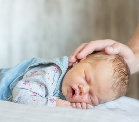 father's hand stroking a newborn baby