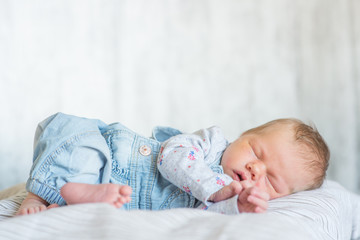 sleeper newborn baby in a denim jumpsuit