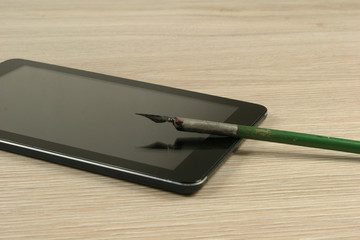 fountain pen and tablet computer on wooden table