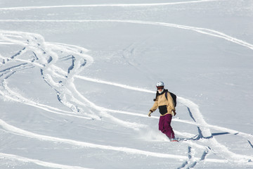 women snowboarder snowboarding on fresh white snow with ski slope on Sunny winter day
