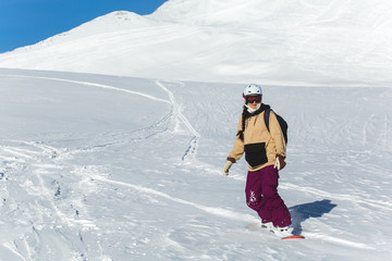 women snowboarder snowboarding on fresh white snow with ski slope on Sunny winter day
