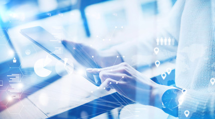Concept of virtual screen,digital connection icon and graph interfaces.Young businesswoman working on modern mobile tablet while sitting at work place at sunny office.Blurred background.