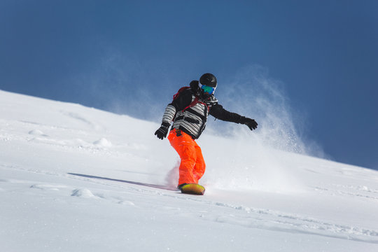  snowboarder snowboarding on fresh white snow with ski slope on Sunny winter day