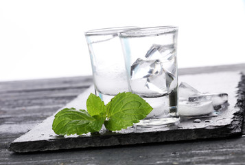 Vodka in shot glasses and ice on rustic wood background