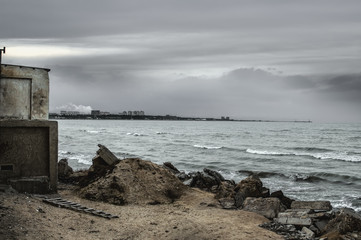 Beautiful surreal landscape of abandoned house and ladder on rocky seashore at sunset time. Cloudy weather. Caspian Sea, Azerbaijan,
