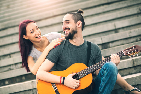 Happy couple in love dating. Man plays guitar to his girlfriend