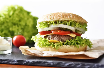 Fresh, delicious burger or cheeseburger with sauces and fresh ingredients. Hamburger on a slate plate.