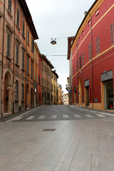 Italy. Emilia-Romagna. Cesena. Narrow street with red buildings on blue sky background. Vertical view.