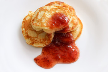 Pancakes doused in strawberry jam on a white plate.Organic, natural, environmentally friendly foods. Made with your own hands.