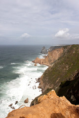 Fototapeta na wymiar Portugal. Cabo da roca. Rocks and wave in ocean on sky with clouds background, vertical view.