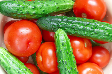 Heap of whole wet tomatoes and cucumbers. Top view point.