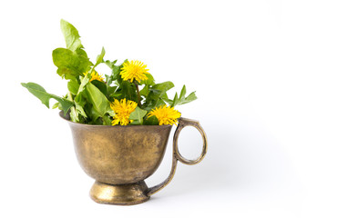 Yellow dandelion flowers in a copper cup