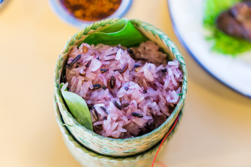 Dark sticky rice inside bamboo container. Cooked black glutinous rice