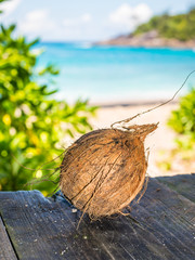 Brown coconut on the old wooden table with wild beach blur background