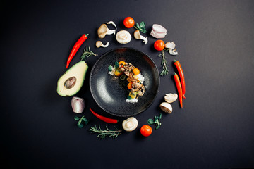 Top view of mushrooms and seasoning ingredients on black table with frame from avocado, mushrooms, tomatoes, onions, chili and greens . Healthy food or vegetarian food concept.