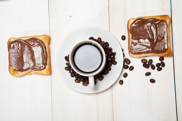 cup of coffee and toast with chocolate on a white wooden table