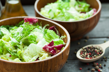 A dish of fresh salad frisse, Romano and radiccio with olive oil, salt and freshly ground percec in a wooden bowl