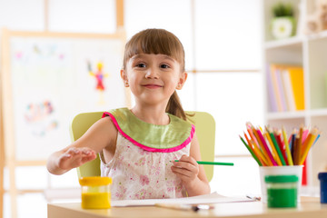 Cute preschooler child girl drawing with pencils in nursery