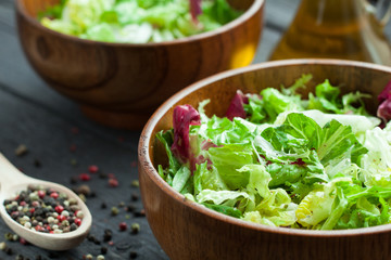 A dish of fresh salad frisse, Romano and radiccio with olive oil, salt and freshly ground percec in a wooden bowl