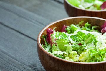 A dish of fresh salad frisse, Romano and radiccio with olive oil, salt and freshly ground percec in a wooden bowl